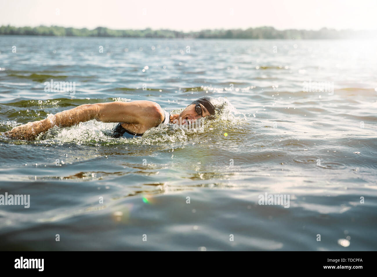 Professional triathlete swimming in river's open water. Man wearing