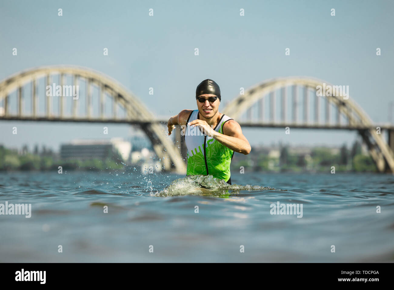 Professional triathlete swimming in river's open water. Man wearing swim equipment practicing