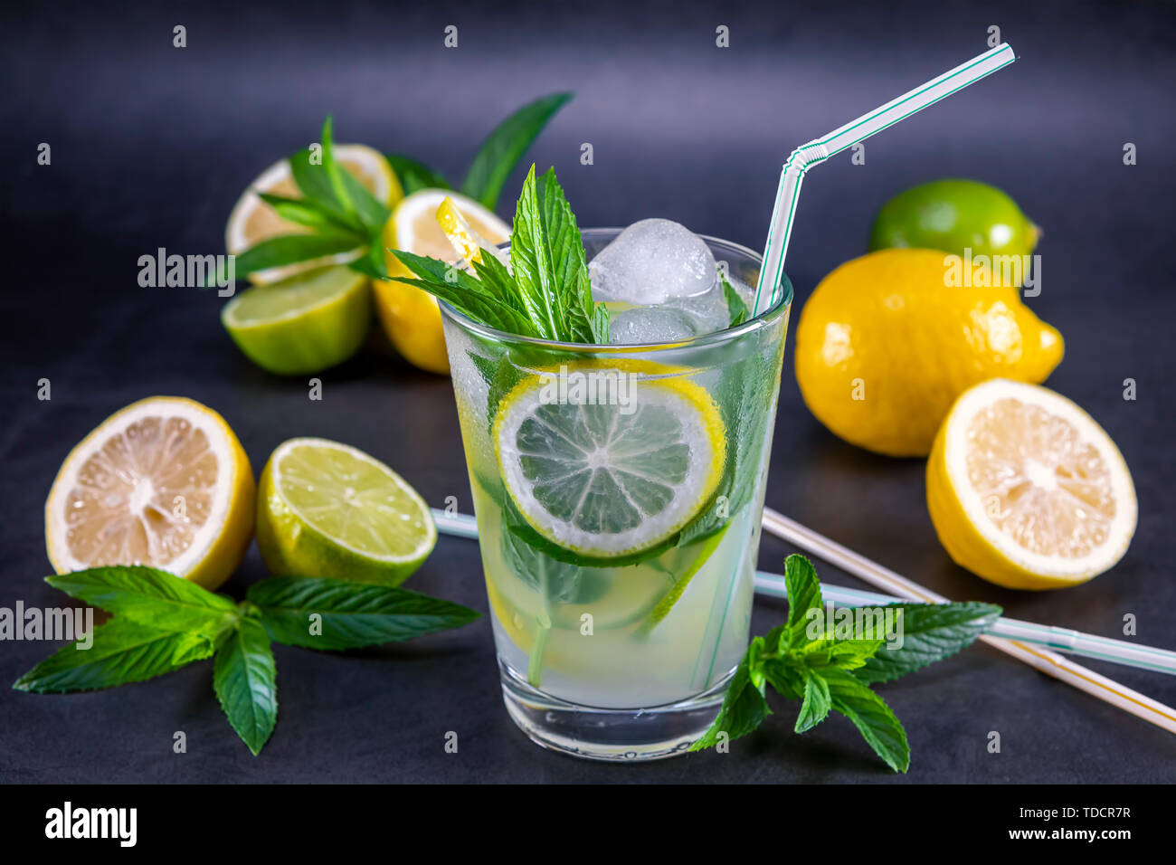 Cold refreshing summer lemonade with mint in a glass on a grey and black background. Focus on leaf in glass. Stock Photo