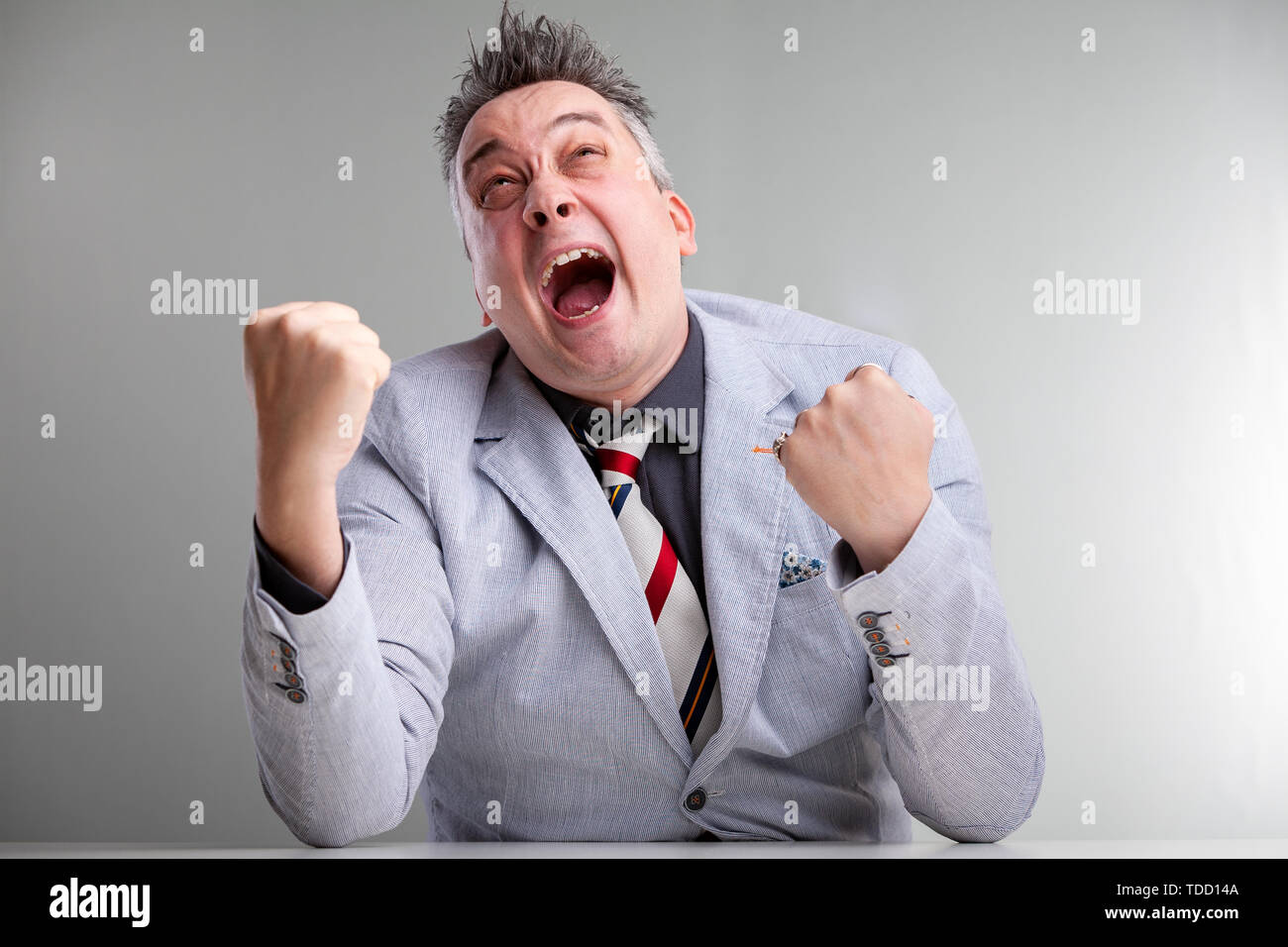 Frustrated angry temperamental businessman clenching his fists and yelling loudly as he vents his stress and rage Stock Photo