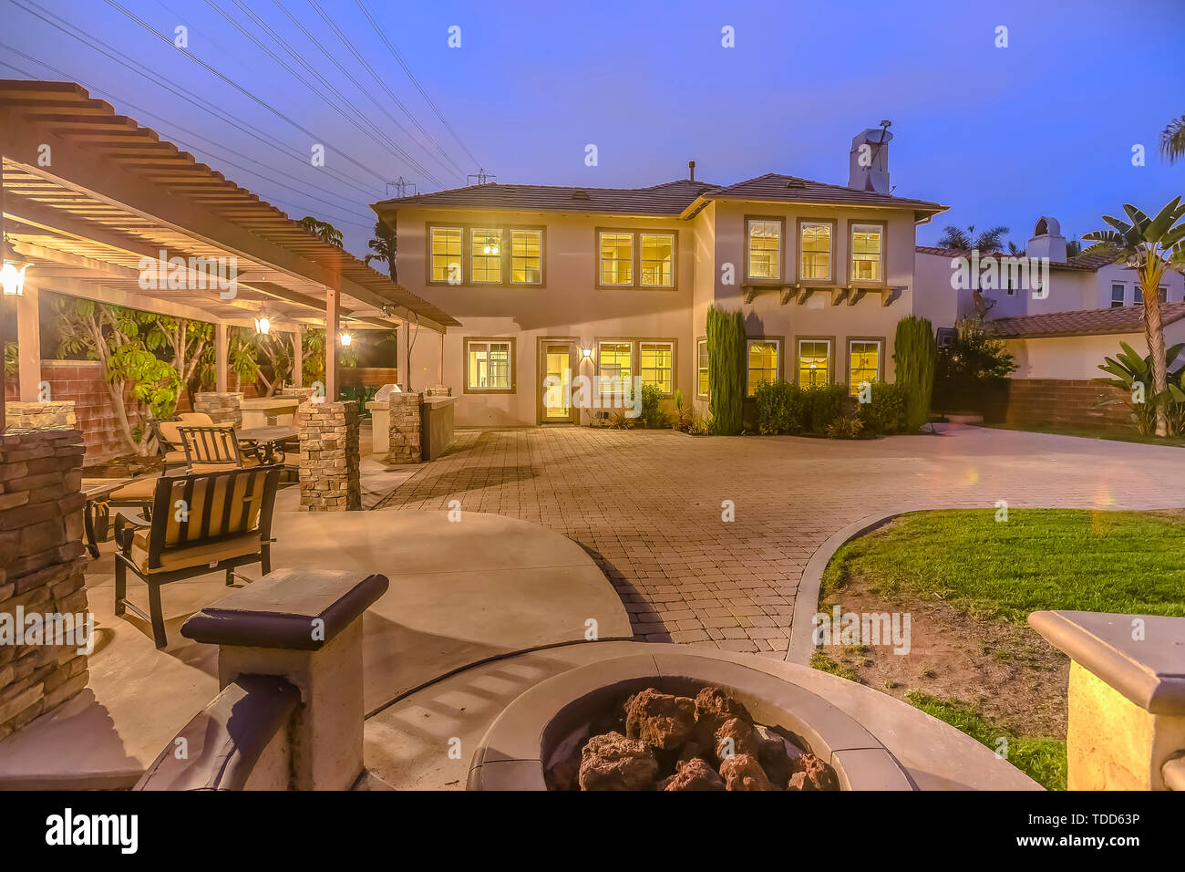 Illuminated House With A Patio Accomodating An Outdoor Dining Area