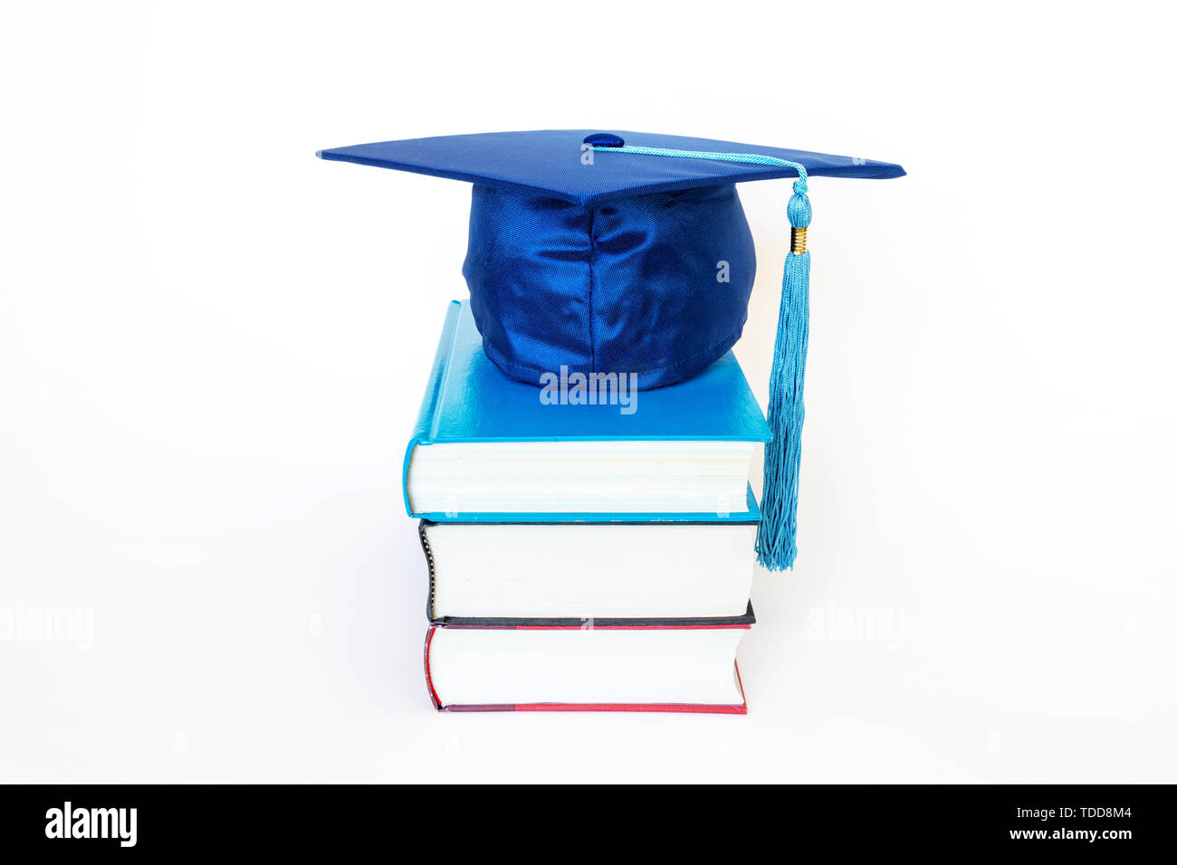 Blue graduation cap on top of books isolated on white background. Education concept. Stock Photo