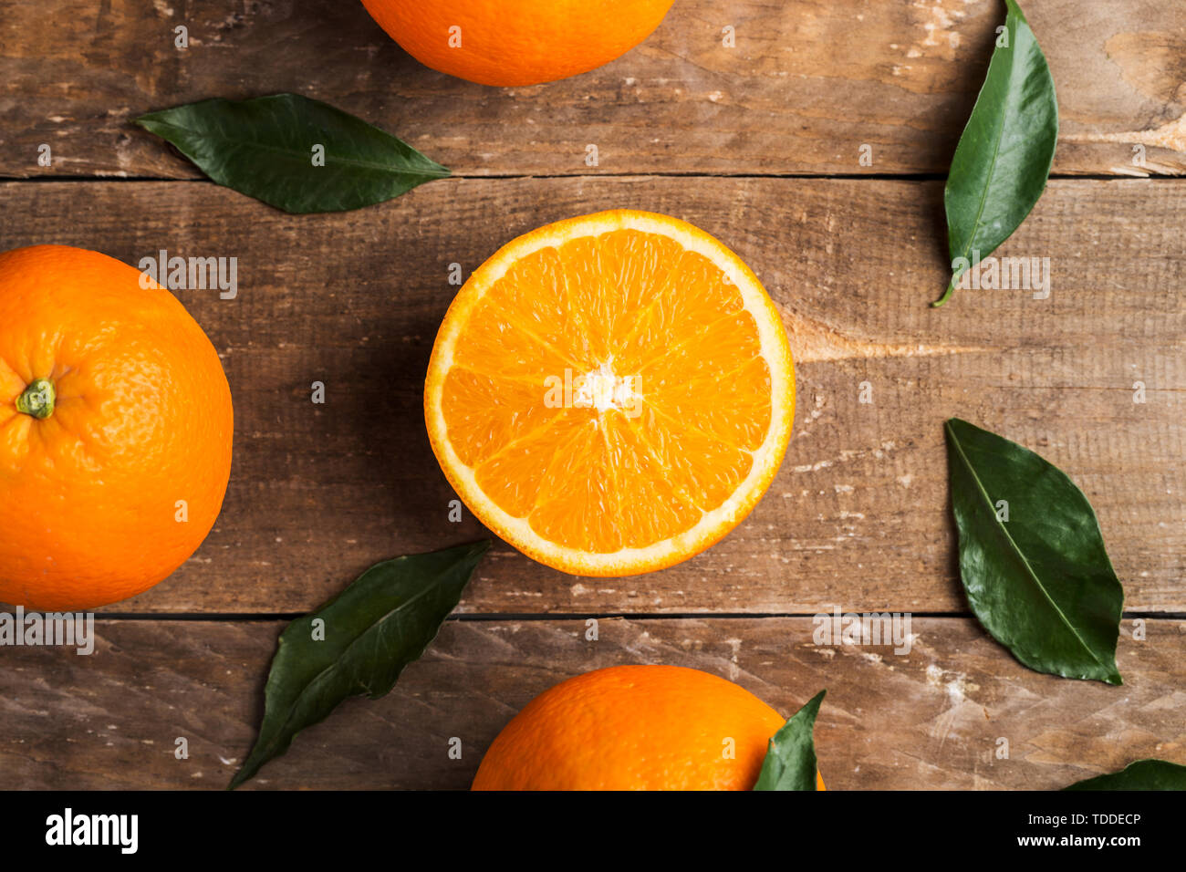 Fresh oranges and leaves on wooden board background Stock Photo