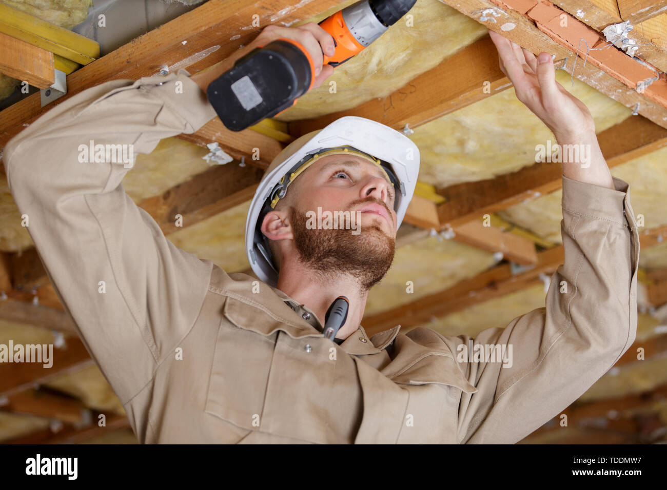 happy builder drilling a wood ceiling Stock Photo