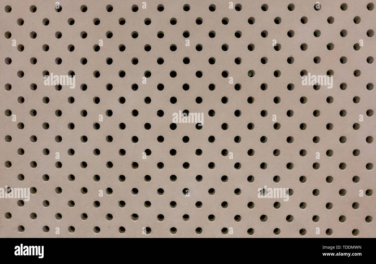 Concrete wall with small uniform drilled holes background Stock Photo