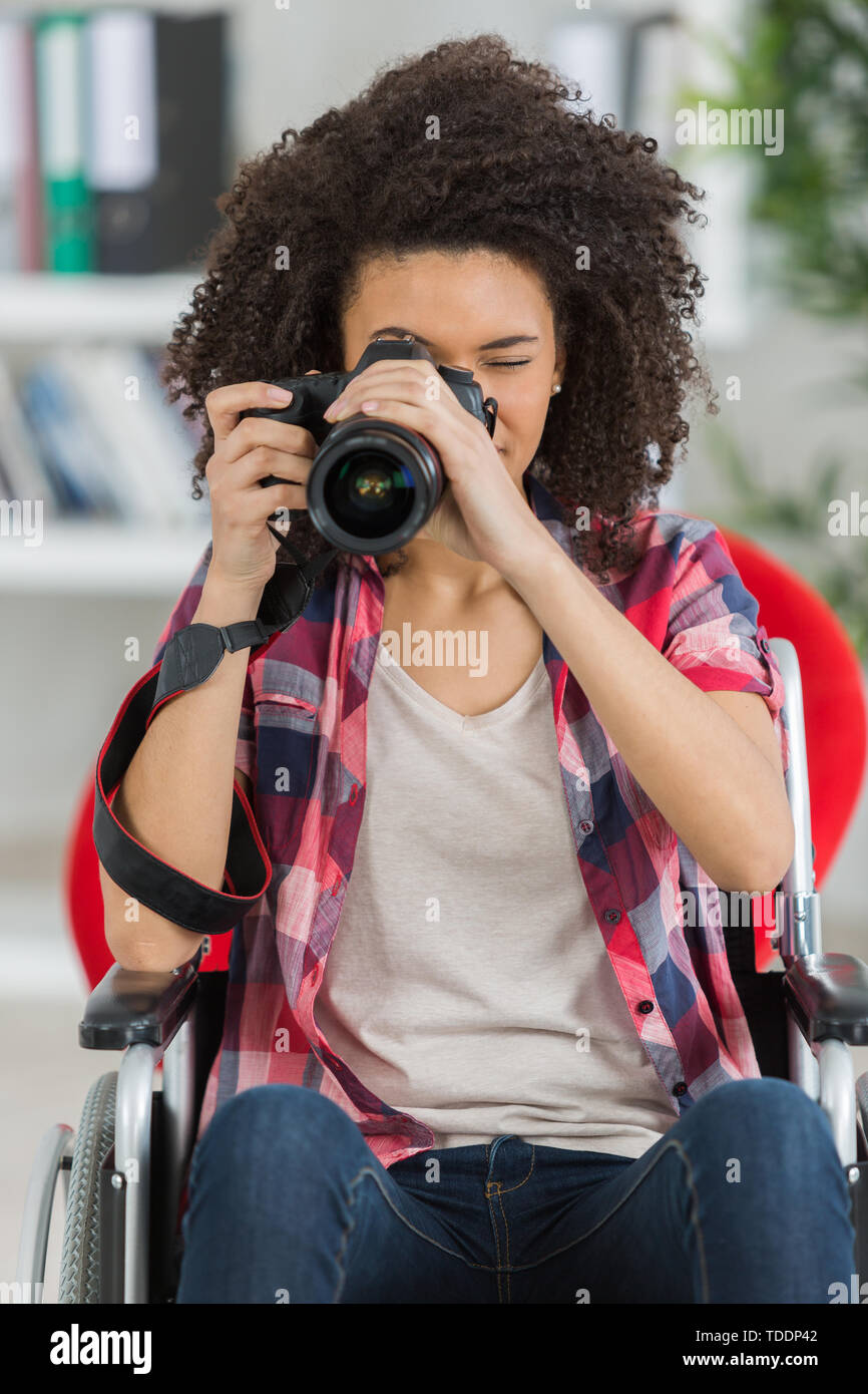disabled mixed-race woman taking pictures with dslr camera Stock Photo
