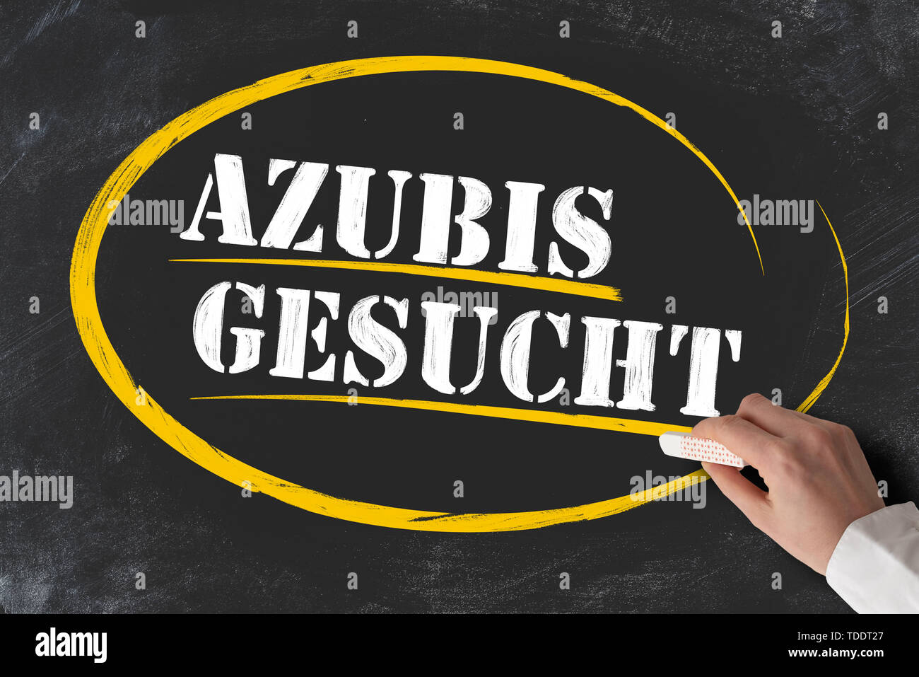 hand holding piece of chalk against blackboard with text AZUBIS GESUCHT, German for apprentices or trainees wanted Stock Photo