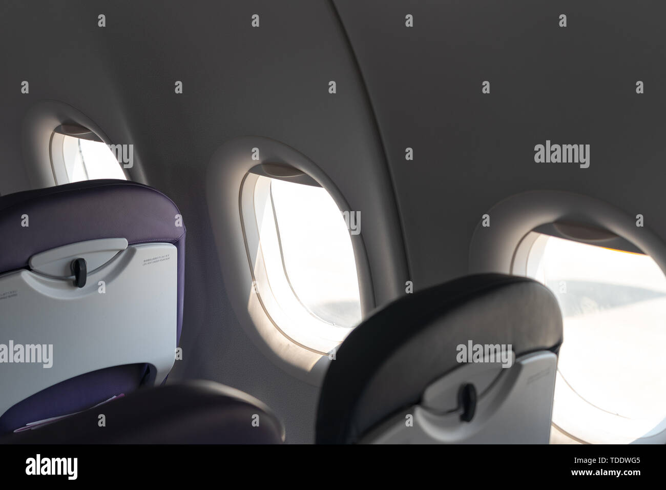 Airplane seats in the cabin economy class and the windows of the airplane. A view of porthole window on board an airbus for your travel concept or pas Stock Photo