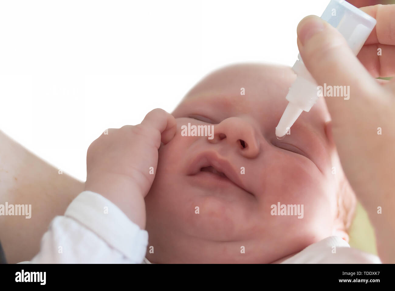 The mother is treating newborn eye inflammation by givining eye drops