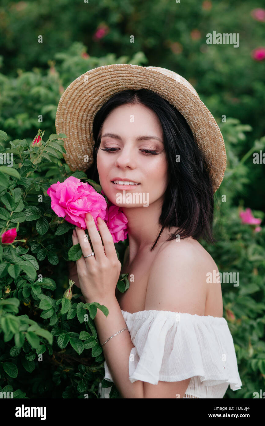 Romantic closeup portrait o charming girl in straw hat smells