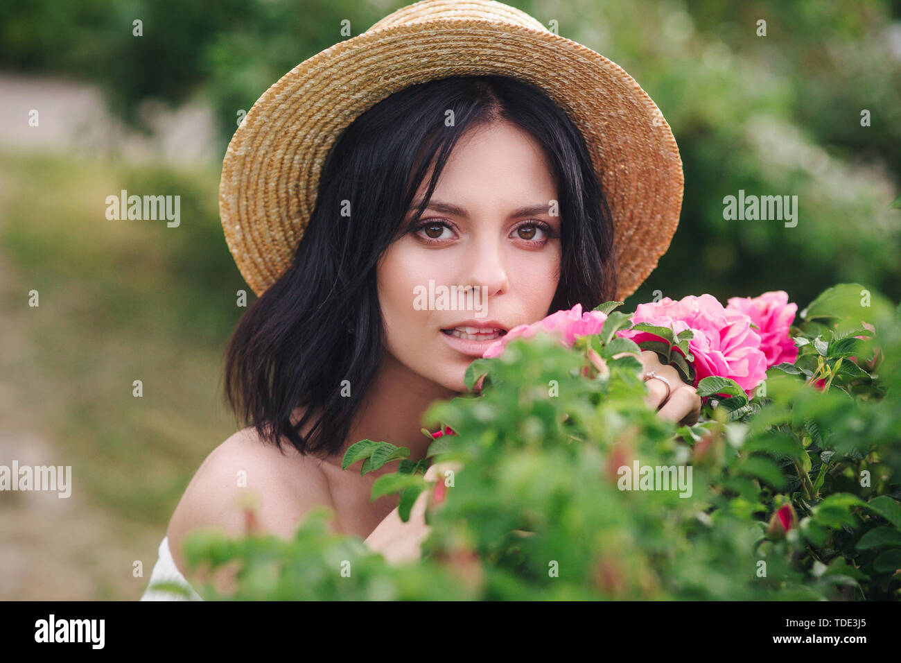 Romantic closeup portrait o charming girl in straw hat smells