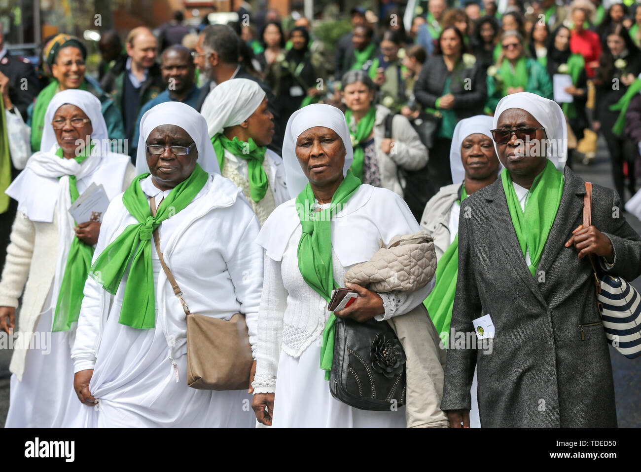 London, UK. 14th June, 2019. Nuns wearing symbolic green scarf take part in a silent marching from St Helen's Church to Grenfell Tower during the commemoration. The Grenfell Tower second anniversary commemoration of the tower block fire. On 14 June 2017, just before 1:00am a fire broke out in the kitchen of the fourth floor flat at the 24-storey residential tower block in North Kensington, West London, which took the lives of 72 people. More than 70 others were injured and 223 people escaped. Credit: SOPA Images Limited/Alamy Live News Stock Photo
