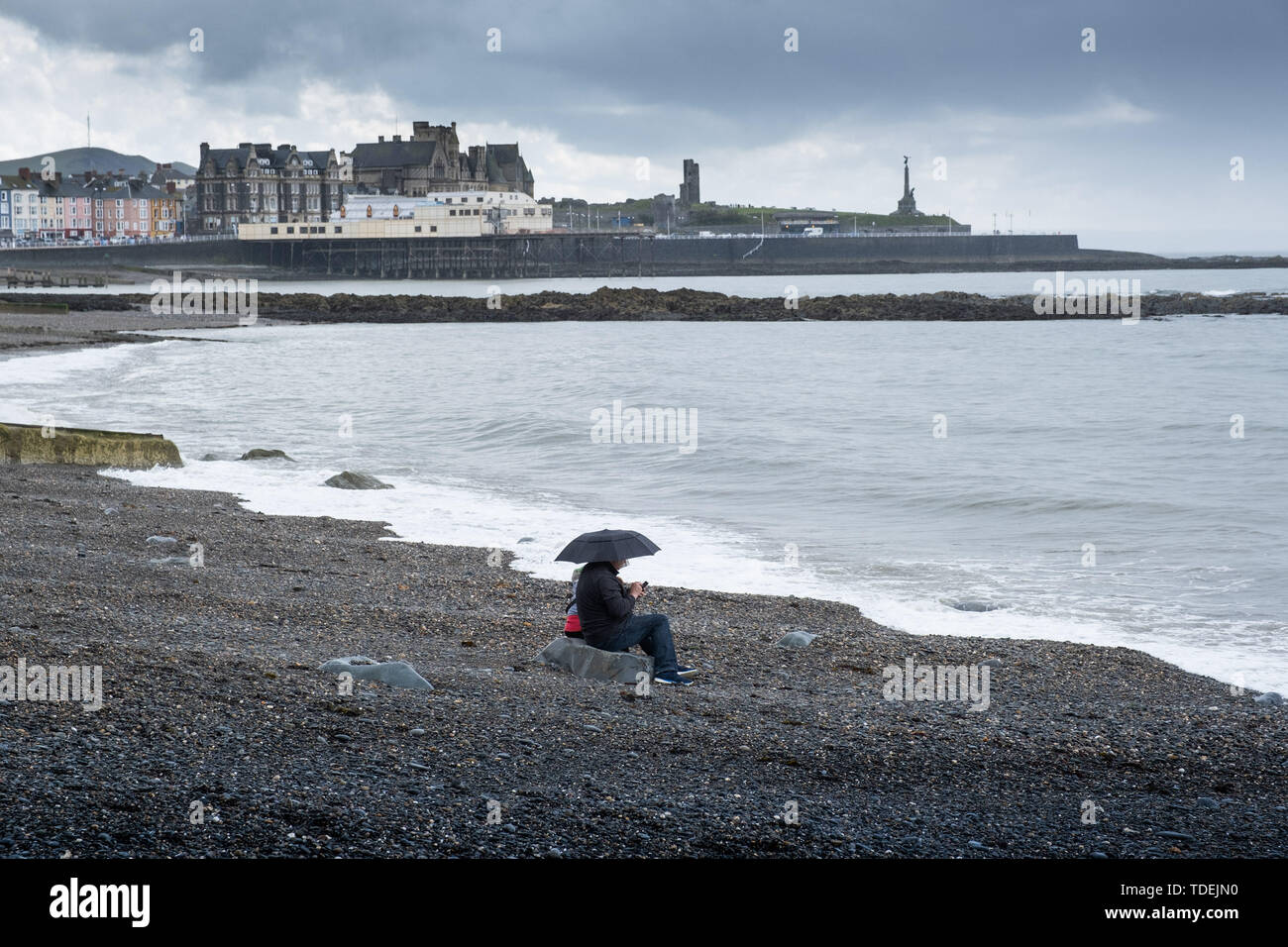 Aberystwyth Wales UK, Saturday 15th June 2019  UK Weather: A couple have the beach to themselves on a grey and wet afternoon at the seaside in Aberystwyth , west wales, as the dreary wet and very unsesonal June ‘summer’ weather continues its hold on the country  photo credit Keith Morris / Alamy Live News Stock Photo