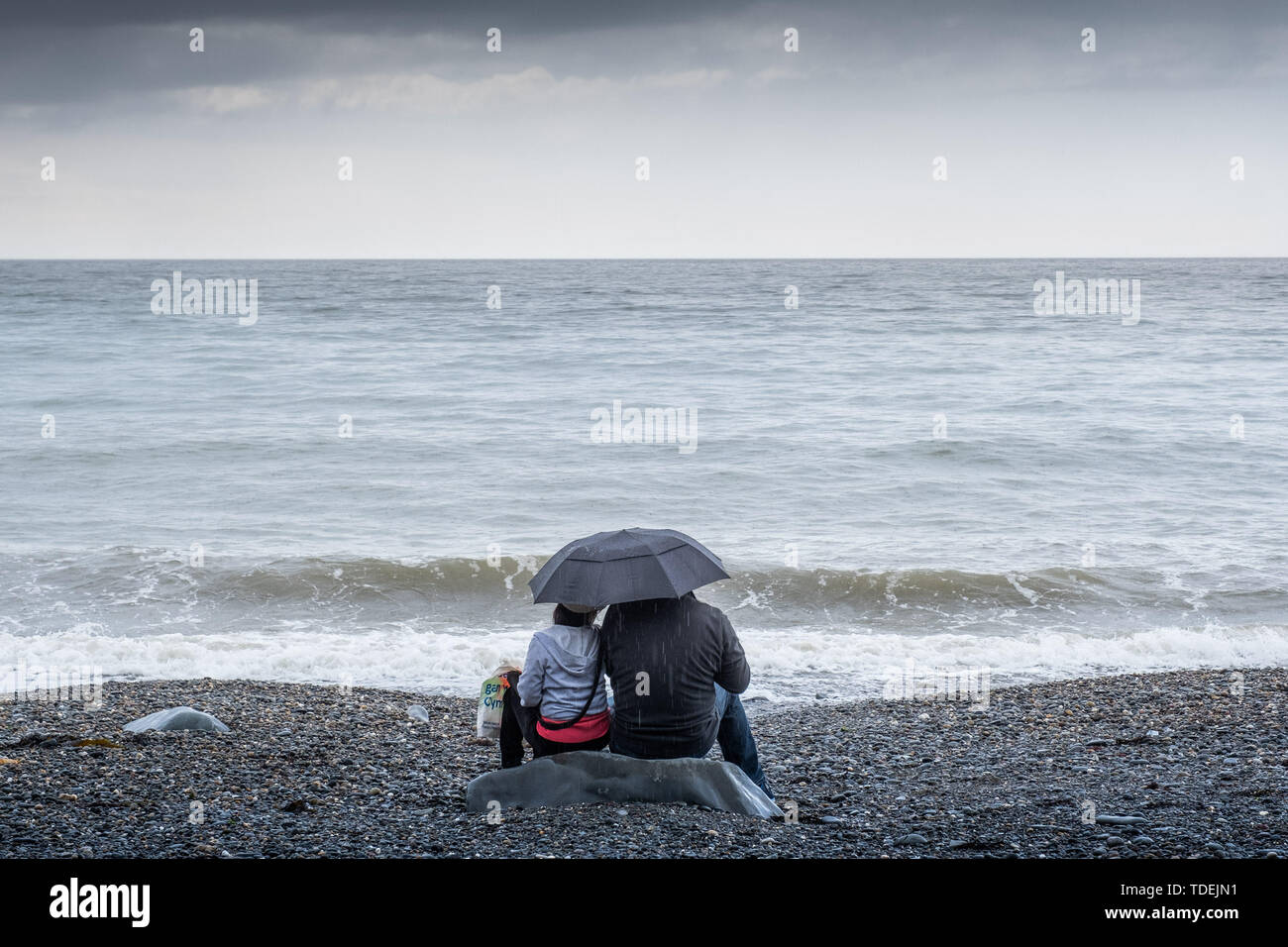 Aberystwyth Wales UK, Saturday 15th June 2019  UK Weather: A couple have the beach to themselves on a grey and wet afternoon at the seaside in Aberystwyth , west wales, as the dreary wet and very unsesonal June ‘summer’ weather continues its hold on the country  photo credit Keith Morris / Alamy Live News Stock Photo