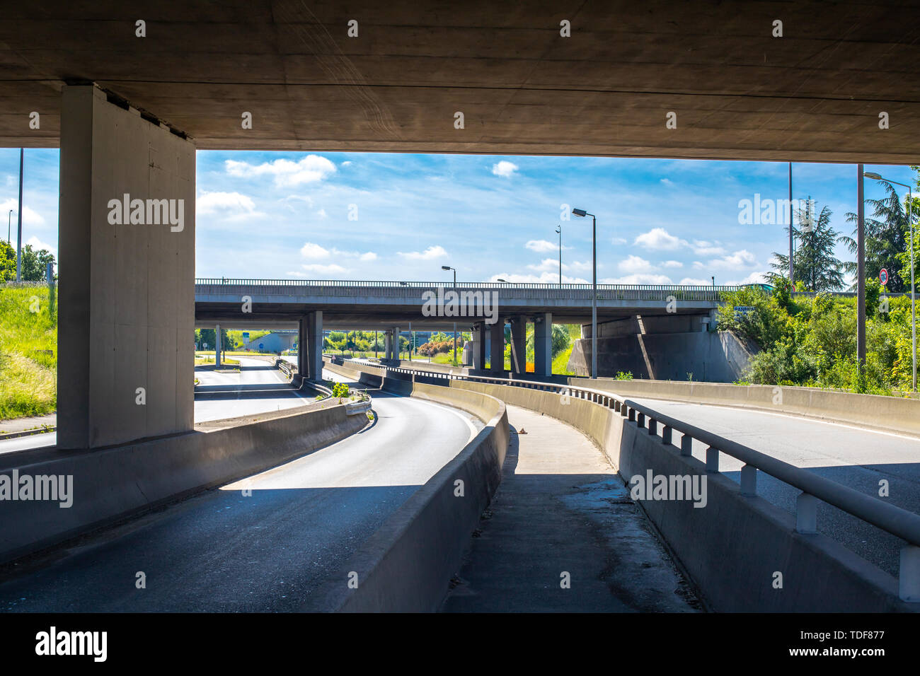 Under the bridge on the motorway. Concrete construction of road junction. Highway in Europe. Between two highways. No cars on highway. Stock Photo