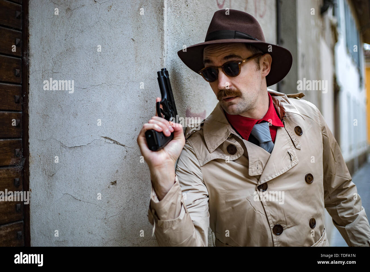 Detective taking cover and aiming with his handgun Stock Photo