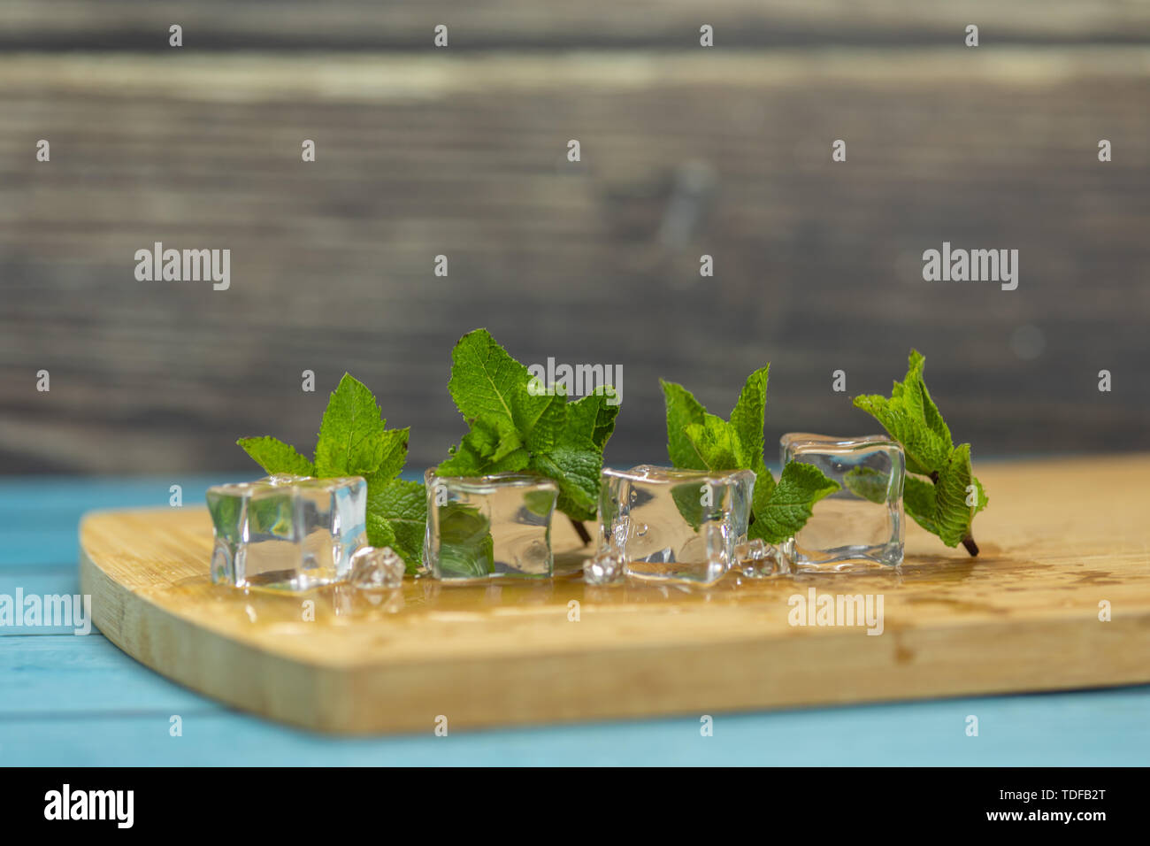 Ice cubes and fresh mint leaves isolated on wooden cutting board. Place ...