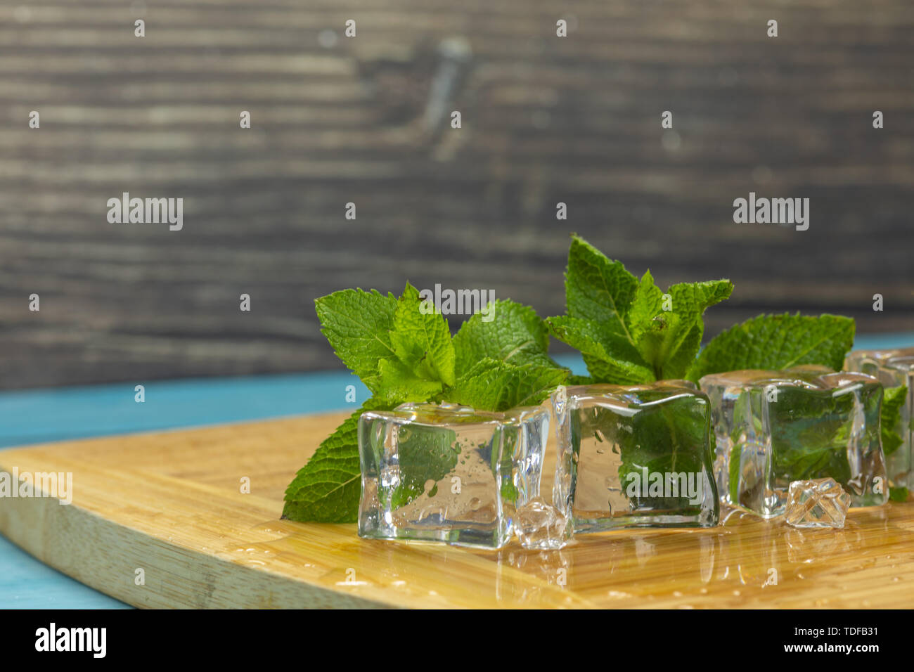 Ice cubes and fresh mint leaves isolated on wooden cutting board. Place ...