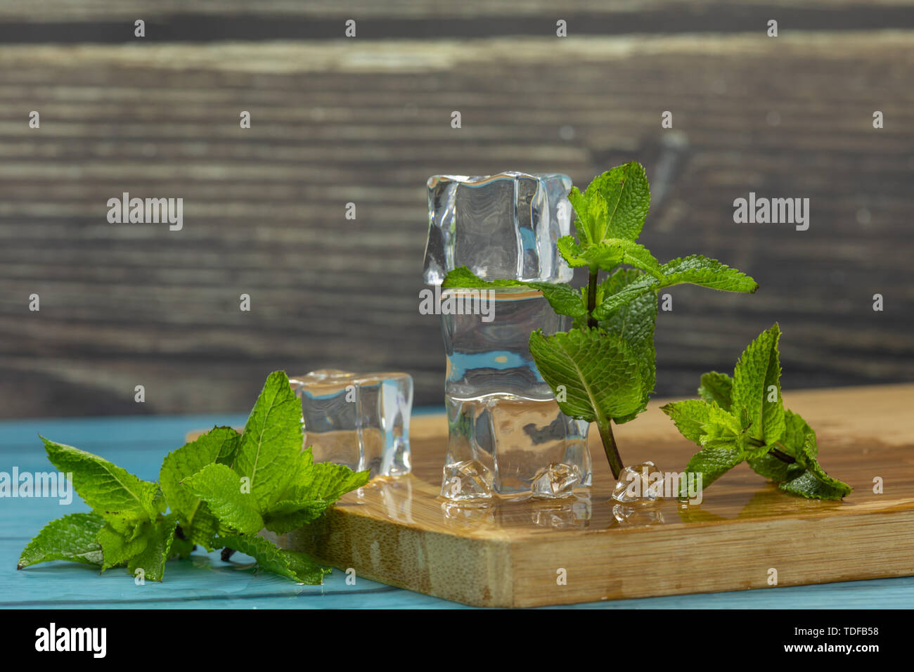 Ice cubes and fresh mint leaves isolated on wooden cutting board. Place ...