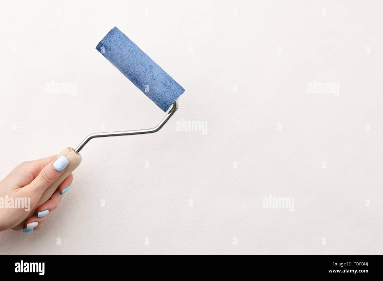 Female hand painting wall with roller in blue color, copy space Stock ...