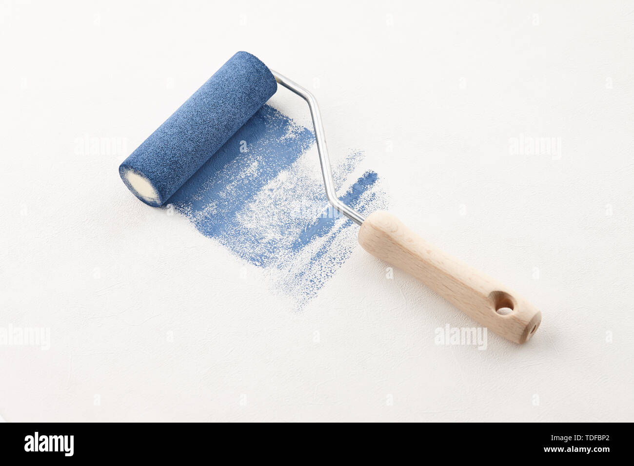 Sponge roller with blue paint on white wallpaper background Stock Photo