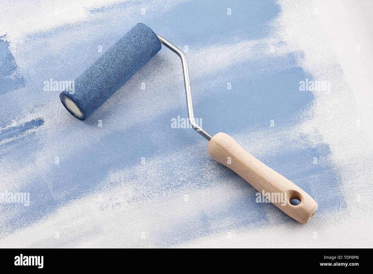 Sponge roller with blue paint on white wallpaper background Stock Photo