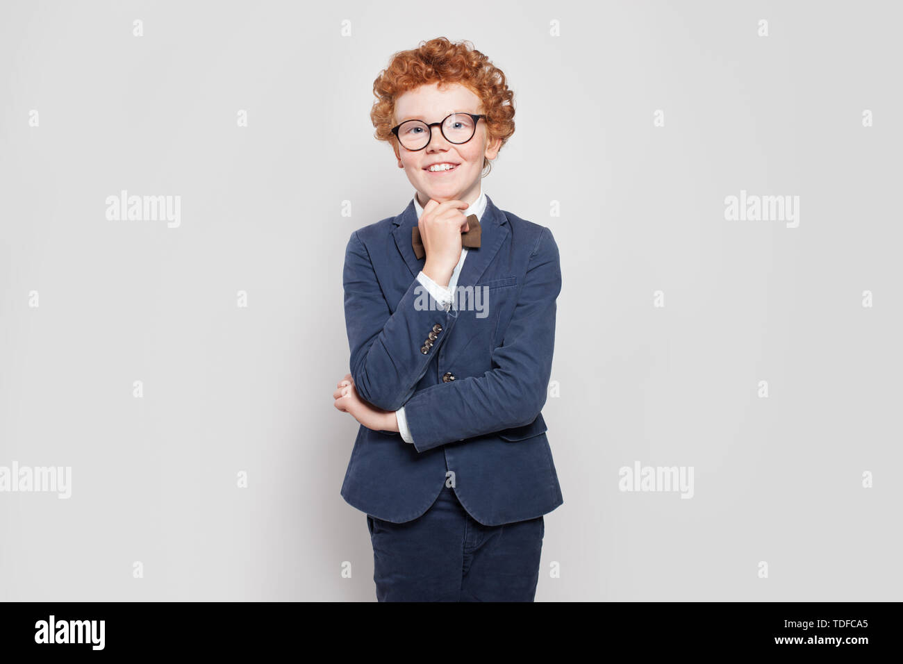 Happy child with ginger hair portrait. Little boy in blue suit standing