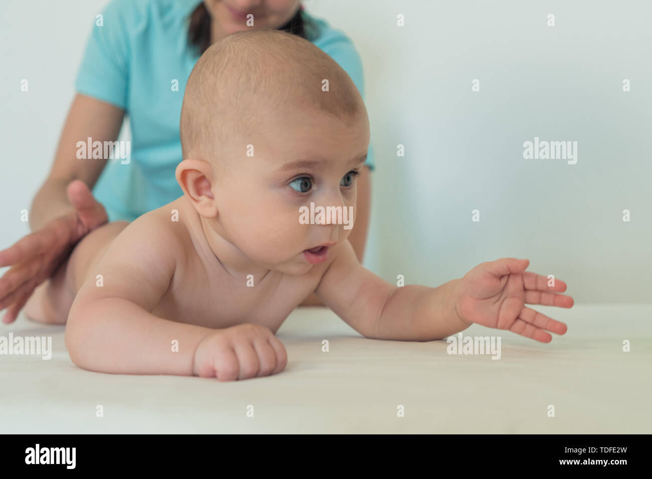 Cute little baby without a diaper looks away in surprise Stock Photo