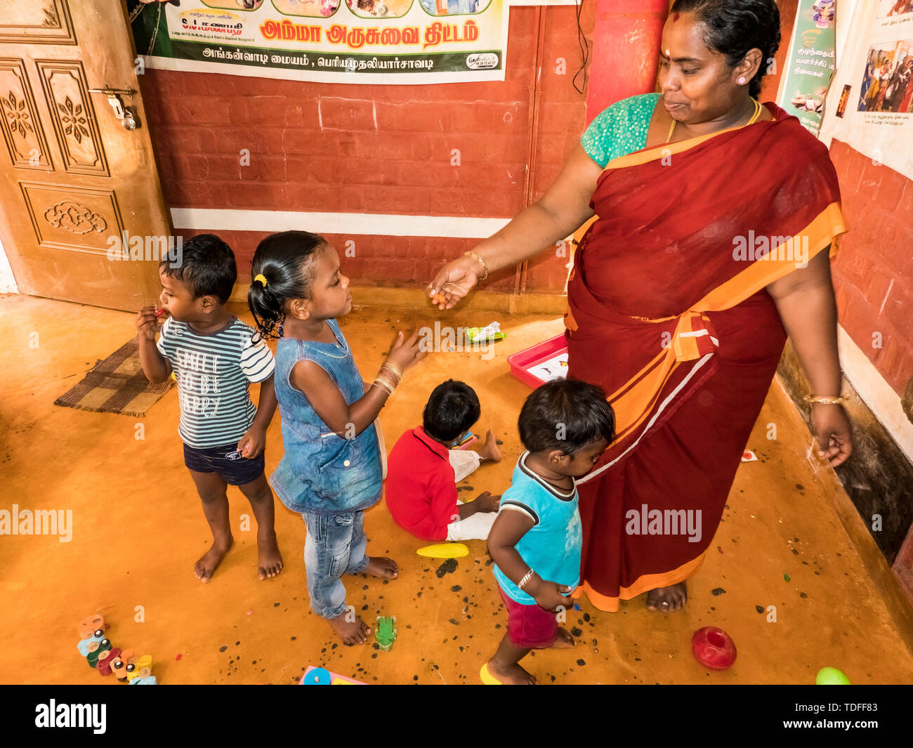 PUDUCHERY, INDIA - DECEMBER Circa, 2018. Poor preschool teacher and her group of kids boys girls having some fun at school with just a few wood toys g Stock Photo