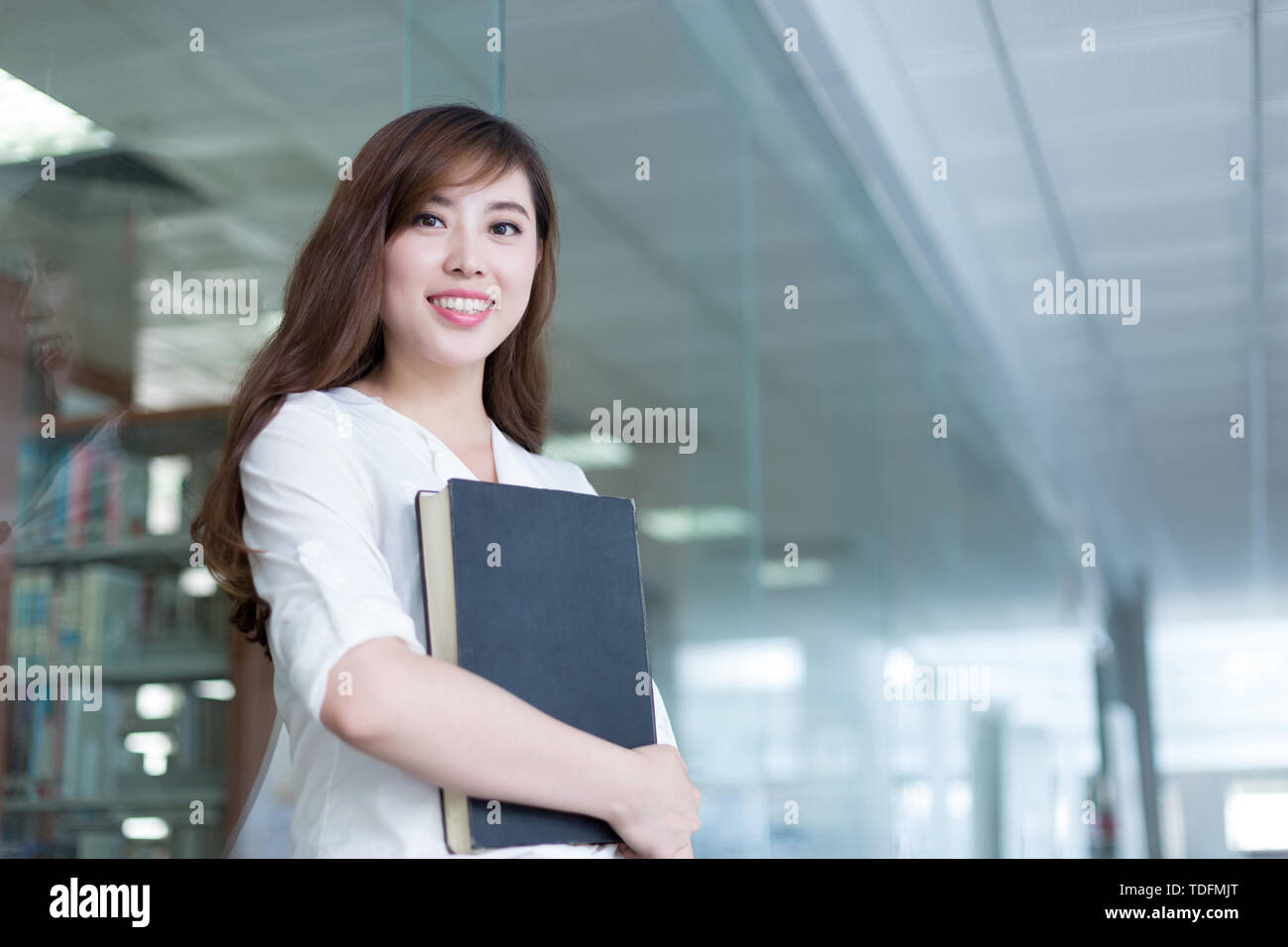 Asian beautiful female student holding book in library Stock Photo - Alamy