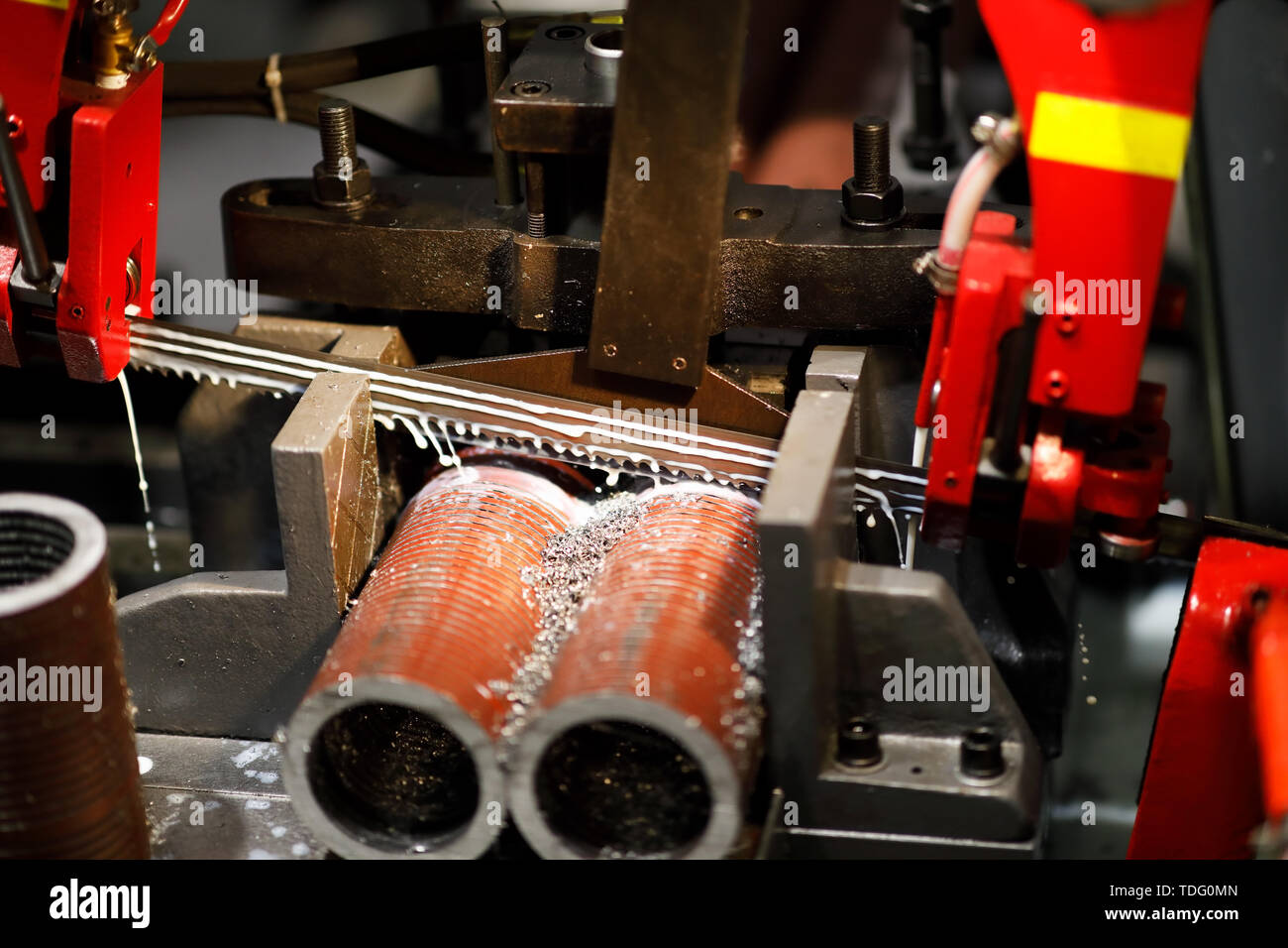 Automatic band saw machine cutting metal pipes with coolant. Selective focus. Stock Photo