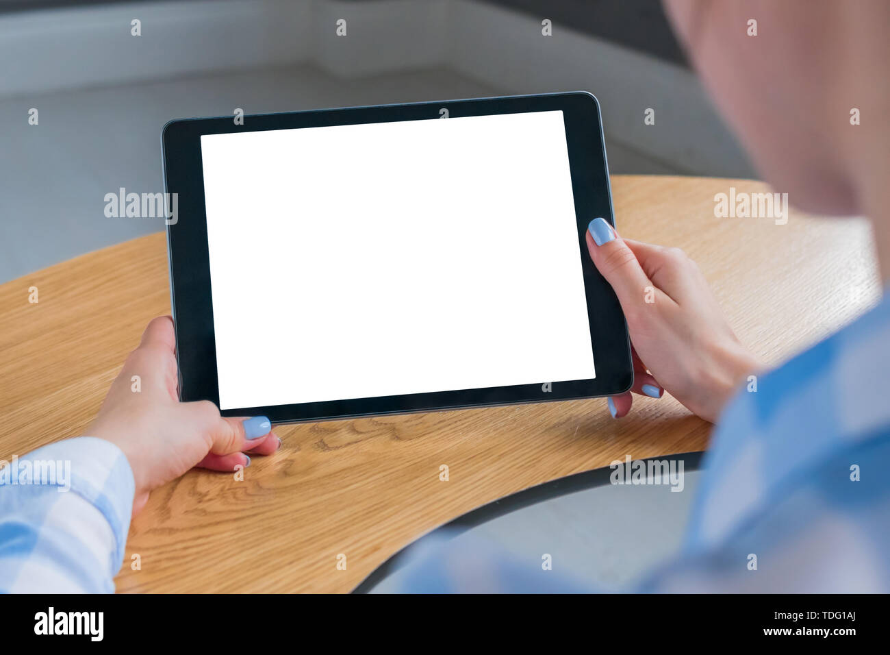 Mockup image: over shoulder close up view of woman looking at modern digital tablet computer device with white blank screen. Mock up, copyspace, leisu Stock Photo