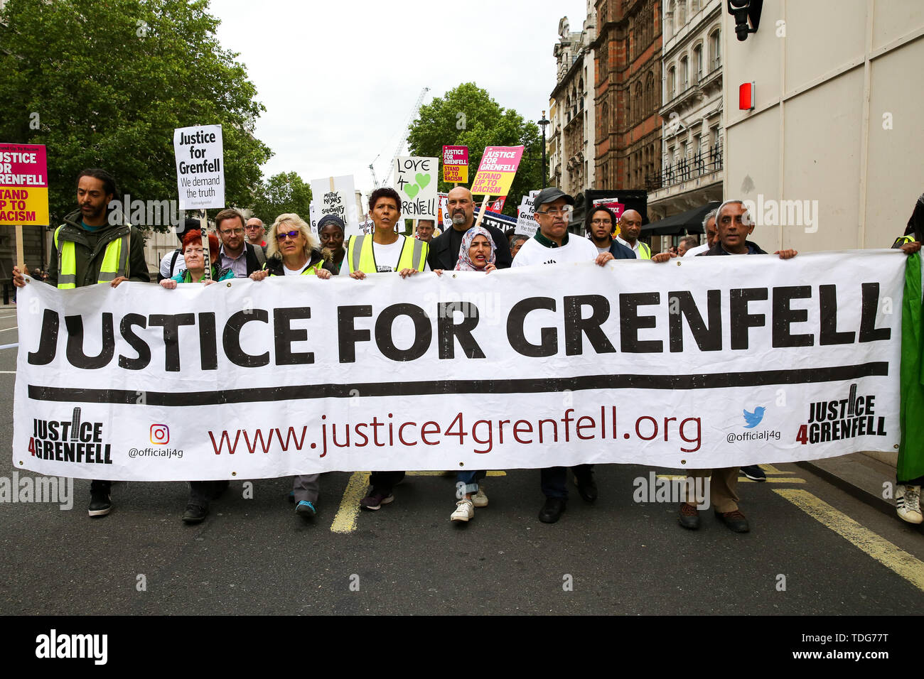 Campaigners hold a banner and placards during the Justice for Grenfell Solidarity rally against the lack of action by the Government following the Grenfell Tower fire, in rehousing affected families, delays in the Public Inquiry, tower blocks still covered in flammable cladding, soil contamination and the performance of Royal Borough of Kensington and Chelsea. On 14 June 2017, just before 1:00 am a fire broke out in the kitchen of the fourth floor flat at the 24-storey residential tower block in North Kensington, West London, which took the lives of 72 people. More than 70 others were injured  Stock Photo