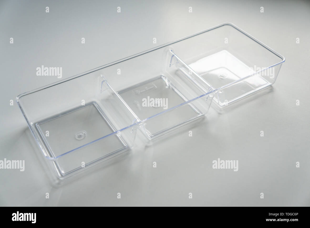 Acrylic clear plastic organizer with 3 square compartments on a white background with empty room space for copy or text. Dividers made of see through  Stock Photo