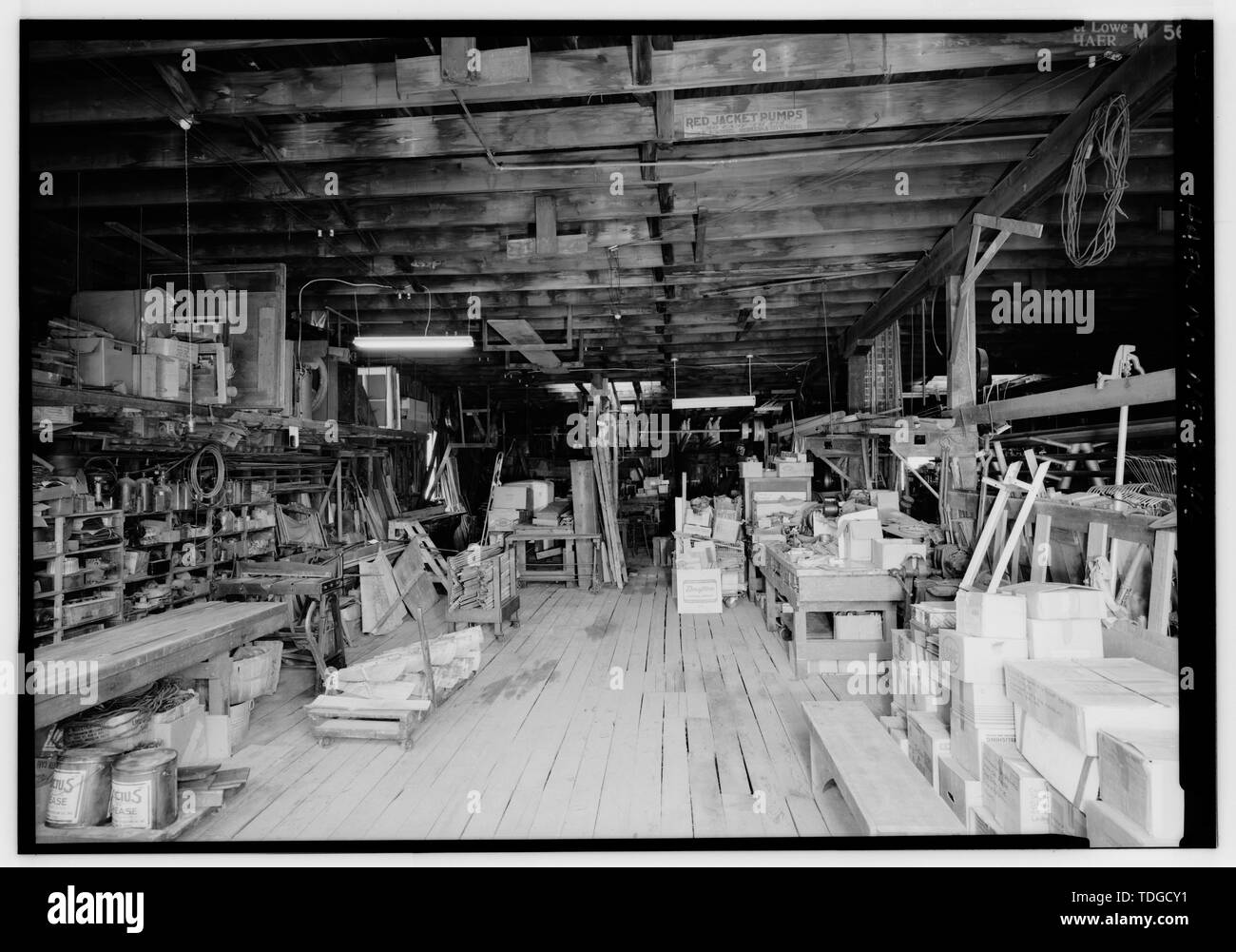 NORTH THROUGH SHEET METAL AND ASSEMBLY AREA IN SOUTHWESTERN QUADRANT OF FACTORY AS SEEN FROM DOORWAY IN SOUTH FRONT WALL. ALONG WEST INTERIOR WALL ARE SHELVES BEARING WATER PUMPS, PARTS FOR PUMPS AND WATER SUPPLY EQUIPMENT, AND NEW OLD STOCK MERCHANDISE. IN FRONT OF THE WALL ARE THE CIRCA 1900 SHEET METAL SHEAR AND CIRCA 1900 SHEET METAL BRAKE. AT THE RIGHT SIDE OF THE IMAGE ALONGSIDE VERTICAL CEILING SUPPORTS IS METAL-COVERED BENCH FOR SHEET METAL WORK. - Kregel Windmill Company Factory, 1416 Central Avenue, Nebraska City, Otoe County, NE Stock Photo