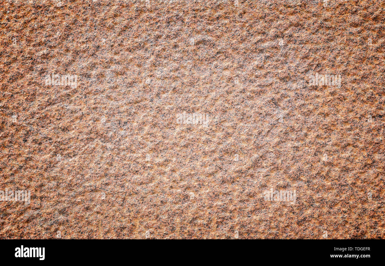Closeup of a bumpy red granite stone wall with High