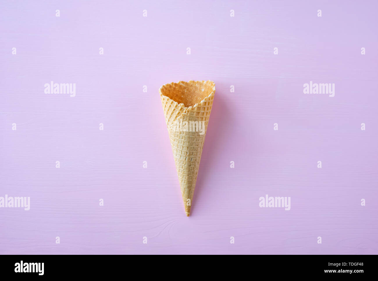Empty waffle cone on pink background. Creative design. Stock Photo