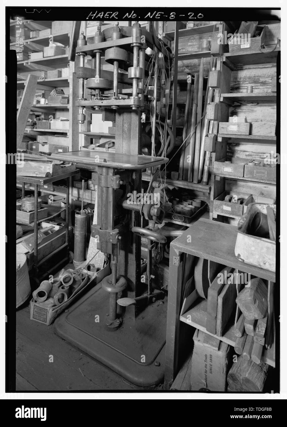 NORTHEAST TO CIRCA 1900 FOUR-SPINDLE PRODUCTION DRILL PRESS ALONG EAST INTERIOR WALL OF FACTORY, SHOWING SHELVES AND BINS WITH TOOLS AND PARTS FOR PUMP AND WATER SYSTEM REPAIR. - Kregel Windmill Company Factory, 1416 Central Avenue, Nebraska City, Otoe County, NE Stock Photo