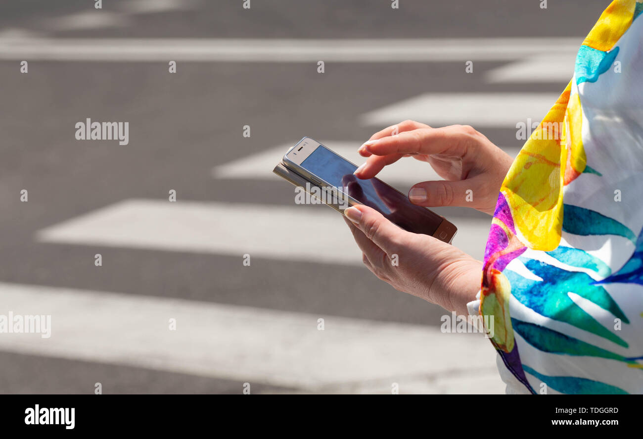 The woman, straring at the phone, crosses the streets / concept Stock Photo