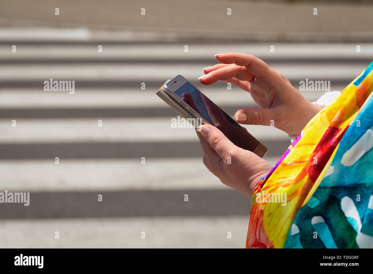 The woman, straring at the phone, crosses the streets / concept Stock Photo