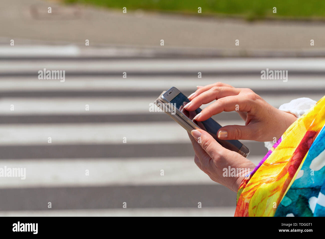 A woaman at a pedestrian crossing looking at the smartphone / safety concept Stock Photo