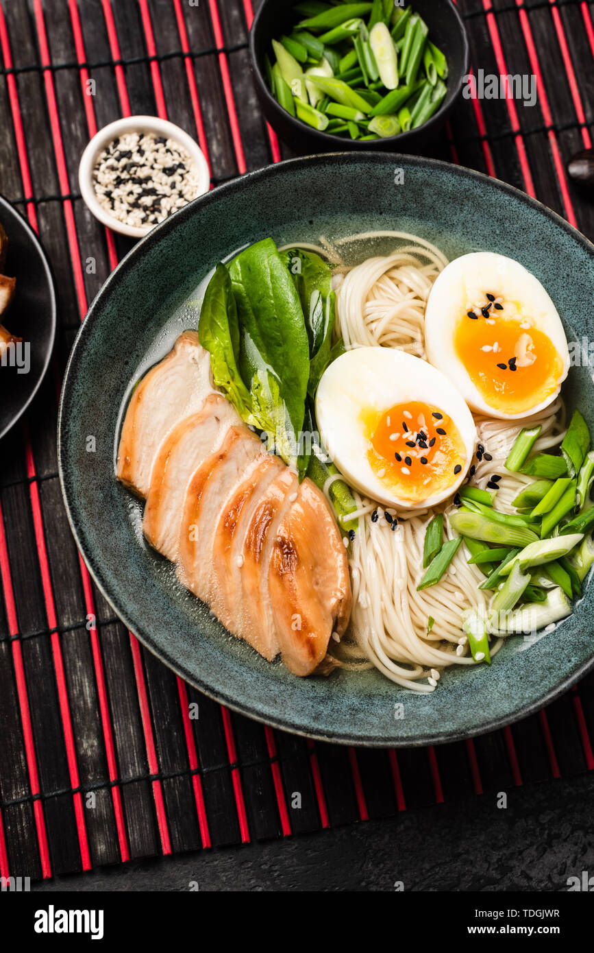 Japanese ramen noodle soup with chicken on red bamboo mat. Top view, vertical orientation Stock Photo