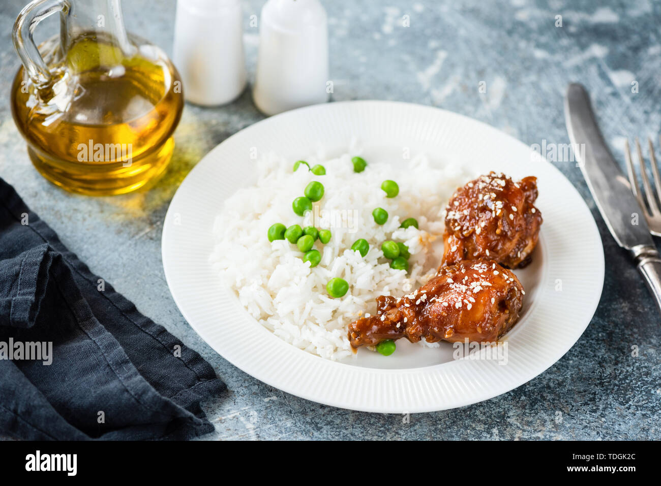 Teriyaki chicken thighs with white rice and green peas on a plate