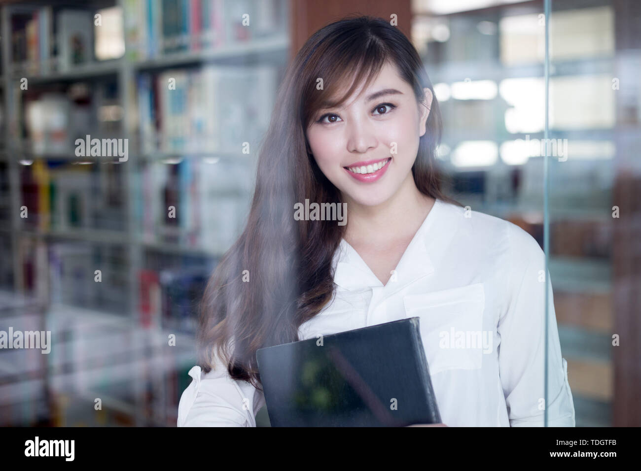 Asian beautiful female student holding book in library Stock Photo - Alamy