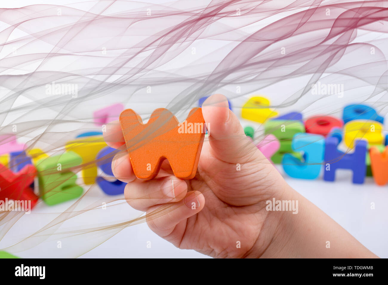 W letter in hand beside alphabet letters scattered randomly Stock Photo ...
