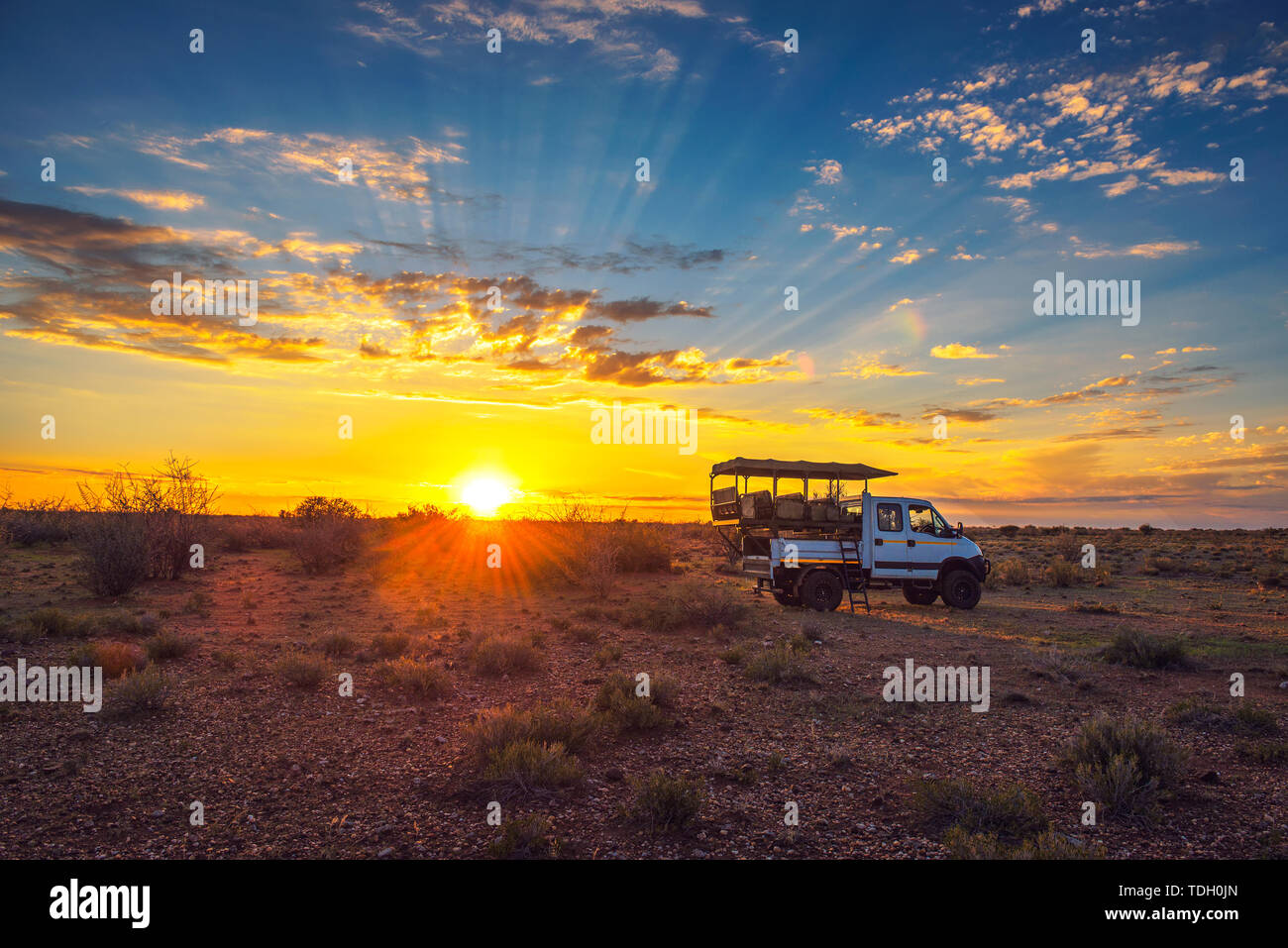 African safari vehicle stops in the Kalahari desert for dramatic sunset Stock Photo