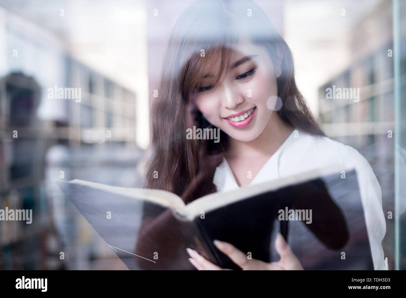 Asian beautiful female student holding book in library Stock Photo - Alamy