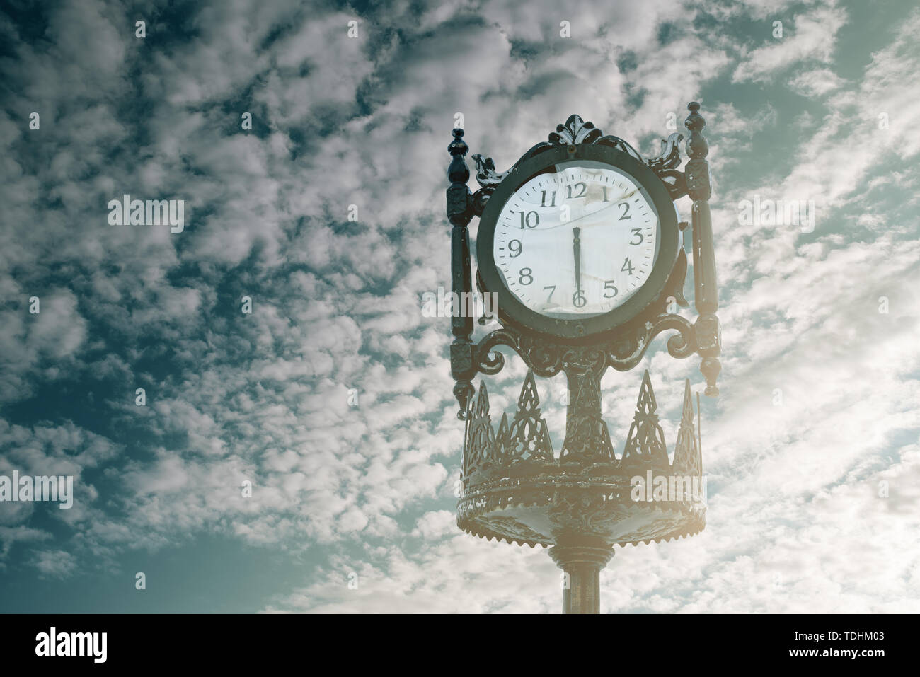 Vintage analogue clock against sunset with beautiful clouds Stock Photo