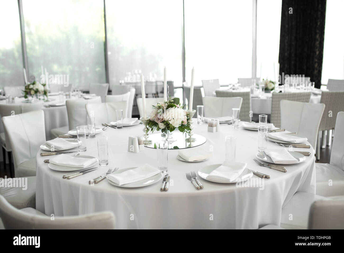 Wedding table setting decorated with fresh flowers. White plates, silverware,  white tablecloth and white room. Wedding floristry. Banquet table for gu  Stock Photo - Alamy