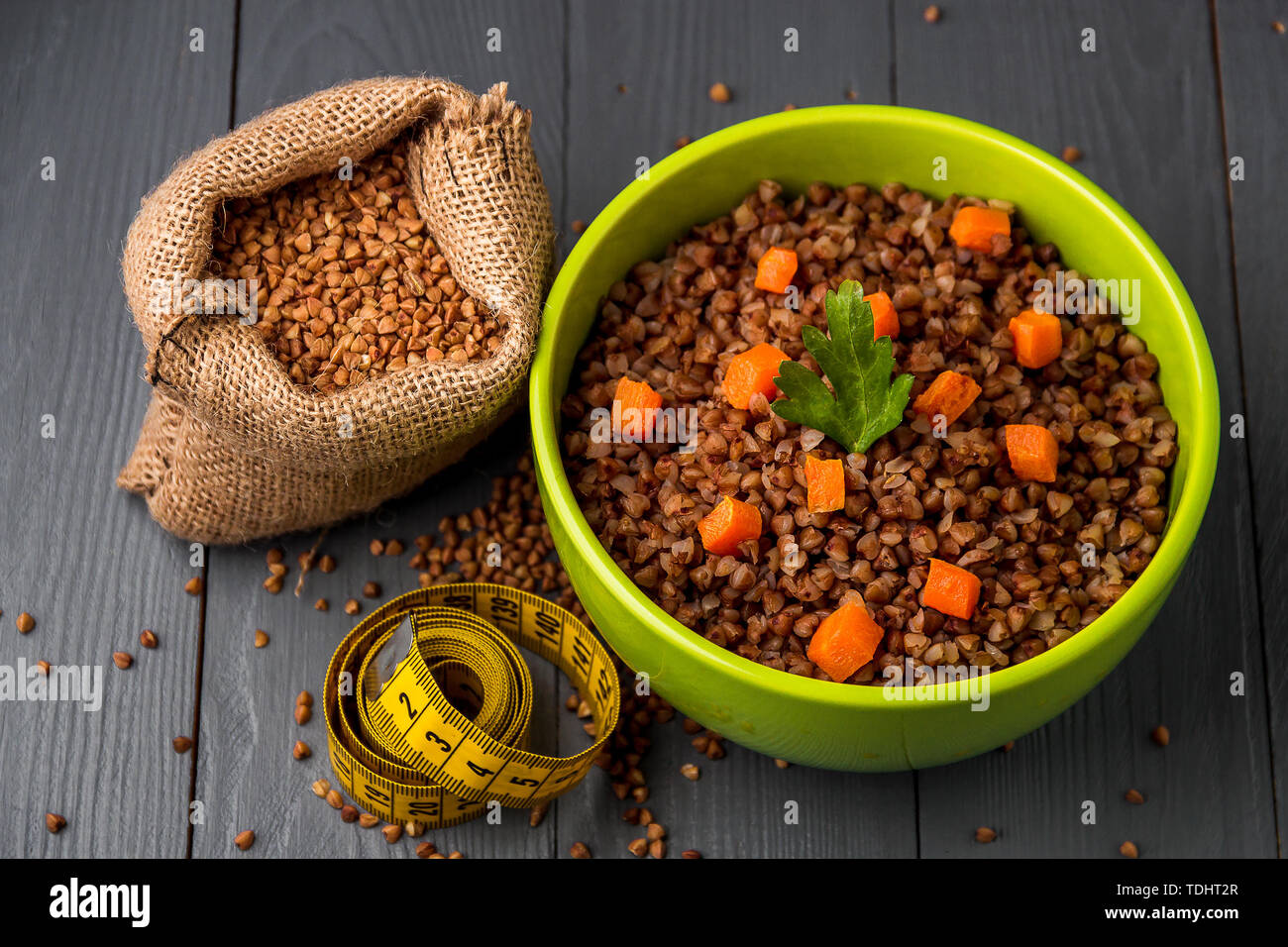 Green bowl of tasty buckwheat porridge on gray wooden table. The concept of a healthy diet. Top view. Stock Photo